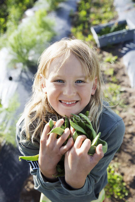 Smiling girl holding beans in garden — Fotografia de Stock