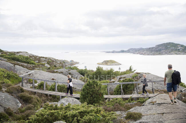 Family hiking over bridge by sea — Photo de stock