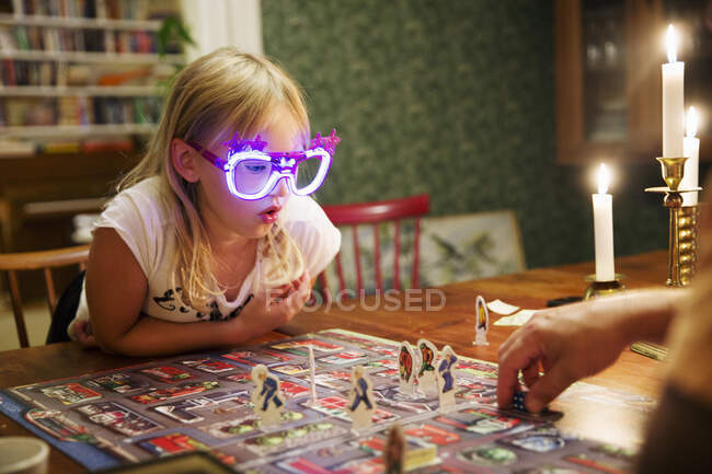 Girl playing board game with her father - foto de stock