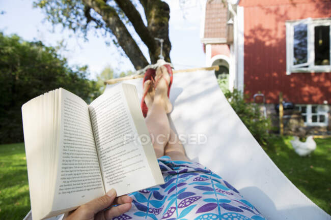 Точка зрения женщины, читающей в гамаке — стоковое фото