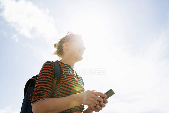 Женщина со смартфоном под солнцем — стоковое фото