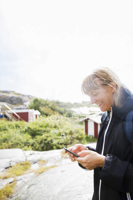 Smiling woman with smart phone under sunshine — Fotografia de Stock