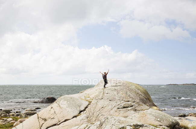 Woman hiking on rock by sea — Stockfoto