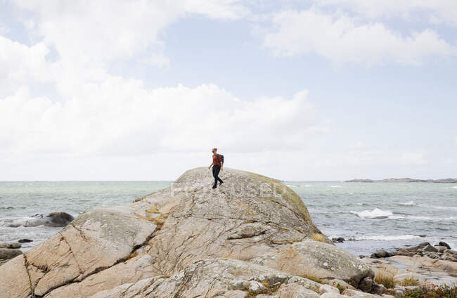 Senderismo de mujer en roca por mar - foto de stock