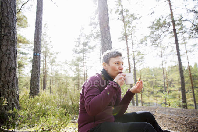 Woman drinking coffee in forest — Stock Photo