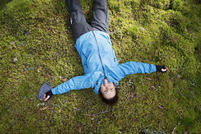Woman lying in moss in forest — Fotografia de Stock