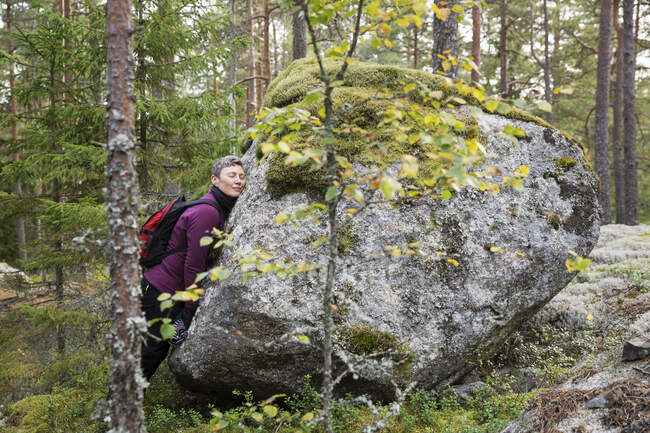 Femme penchée sur le rocher dans la forêt — Photo de stock