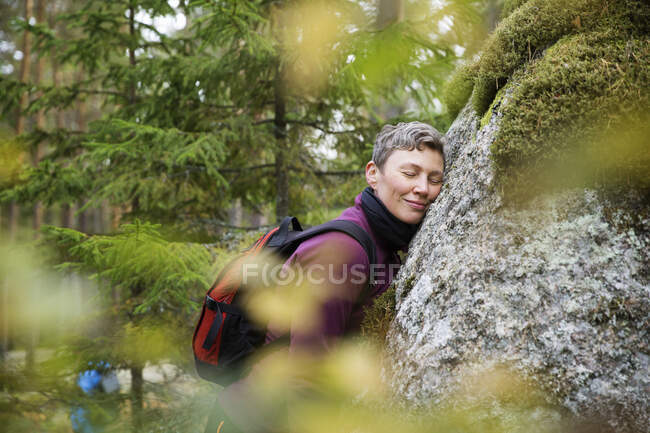 Donna appoggiata sulla roccia nella foresta — Foto stock
