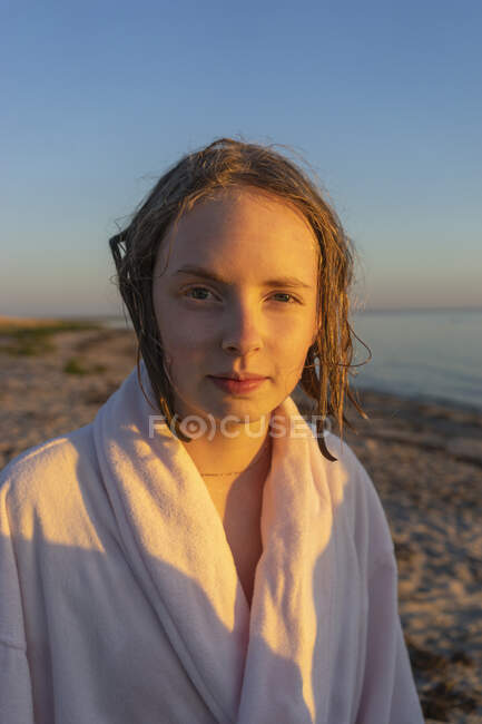 Retrato de menina em roupão de banho na praia ao pôr do sol — Fotografia de Stock