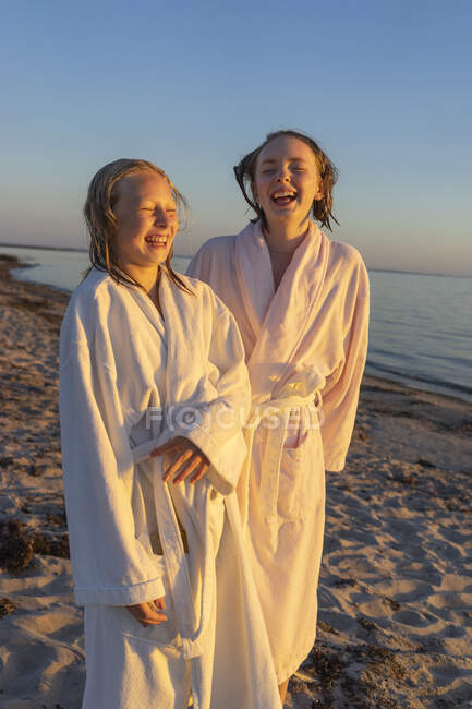Ragazze ridenti in accappatoi sulla spiaggia al tramonto — Foto stock
