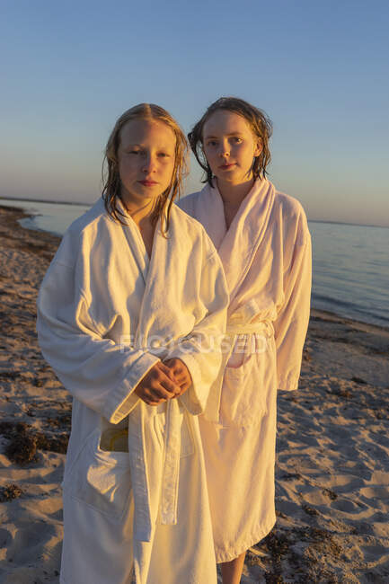 Girls in bathrobes on beach at sunset — Stockfoto