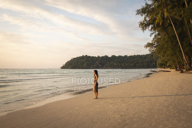 Женщина на тропическом пляже на закате — стоковое фото