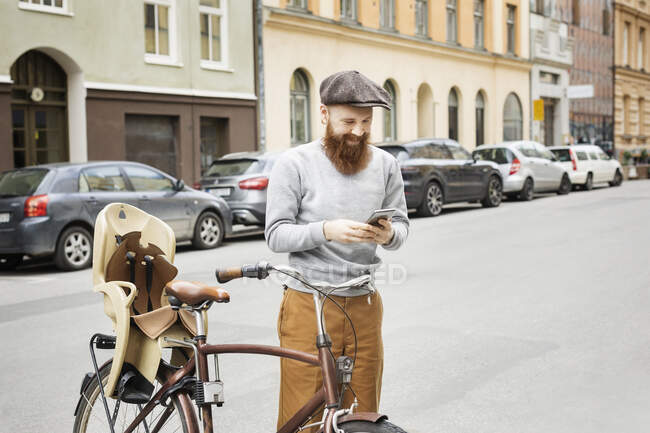 Man using smart phone by bicycle on city street — Stock Photo