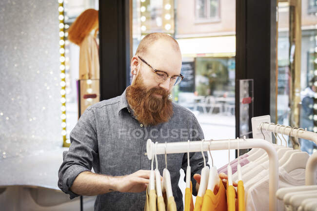 Small business owner organising clothes in store — Fotografia de Stock