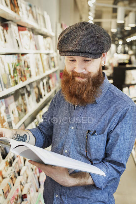 Bearded man reading magazine in store — Stock Photo