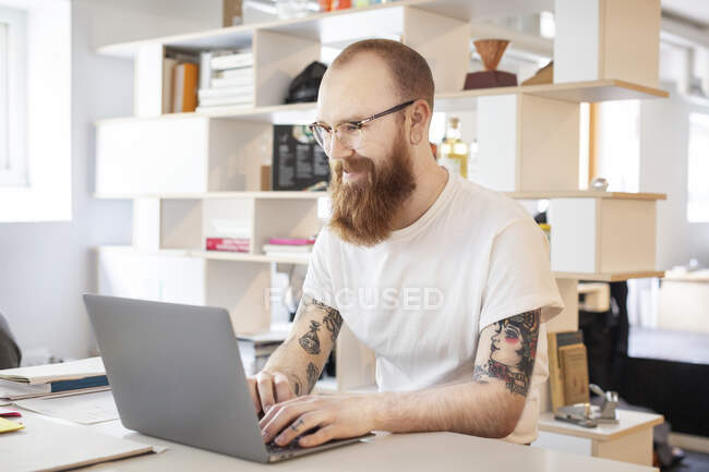 Бородатий чоловік використовує ноутбук за столом — стокове фото