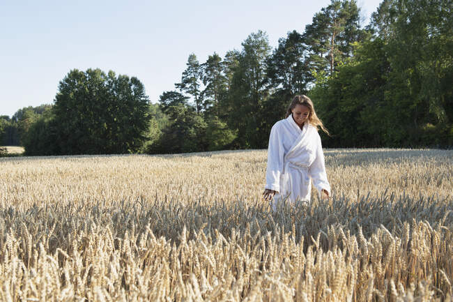Young woman wearing bathrobe in field — Foto stock