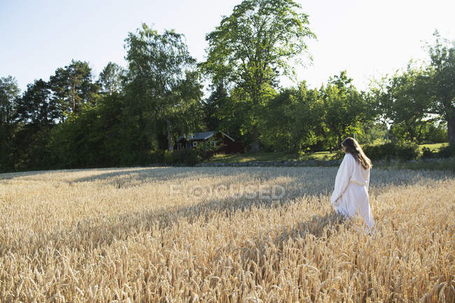 Young woman wearing bathrobe in field — Photo de stock