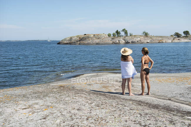 Women standing on rock by sea — Stockfoto