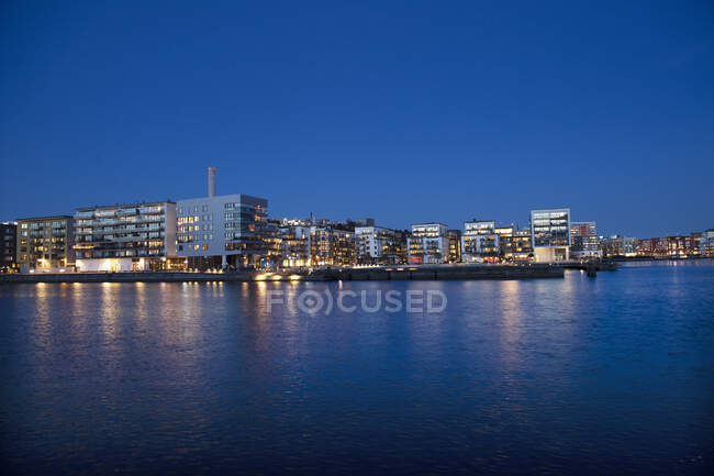 Panoramic view of buildings on waterfront at night in Stockholm, Sweden - foto de stock