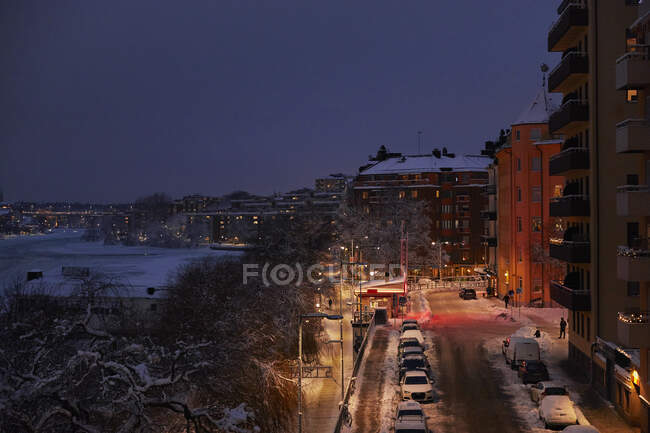 Edificios y coches cubiertos de nieve por la noche en Estocolmo, Suecia - foto de stock