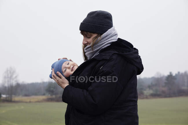 Woman carrying daughter in baby carrier — Fotografia de Stock