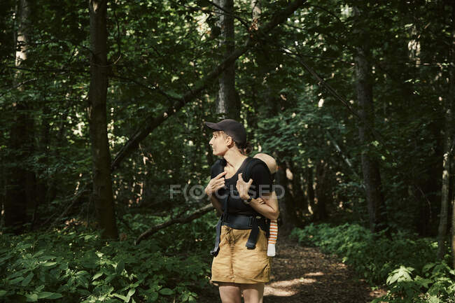 Woman walking through forest with daughter in baby carrier — Fotografia de Stock