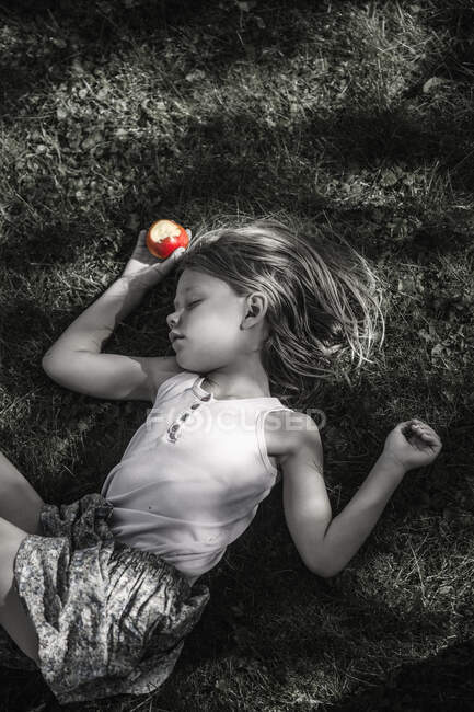 Menina com maçã dormindo na grama — Fotografia de Stock