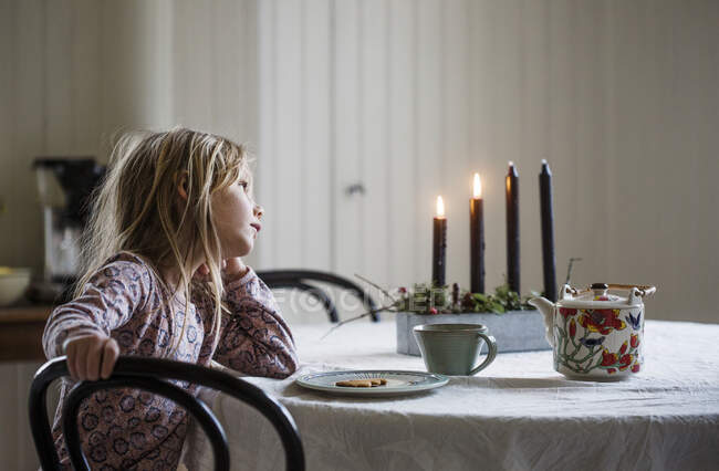 Girl sitting at table with Christmas candles - foto de stock