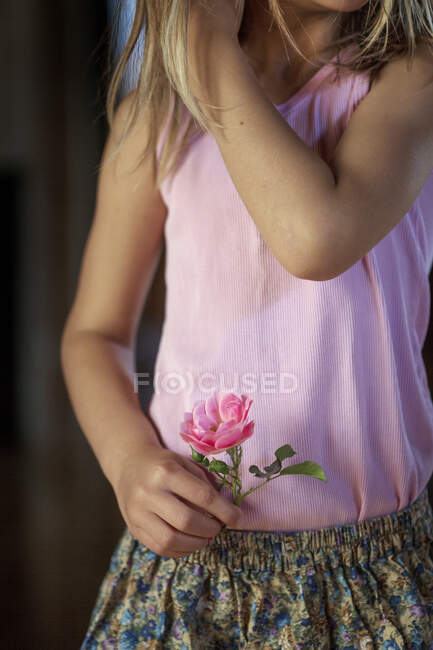 Main de fille tenant fleur rose — Photo de stock