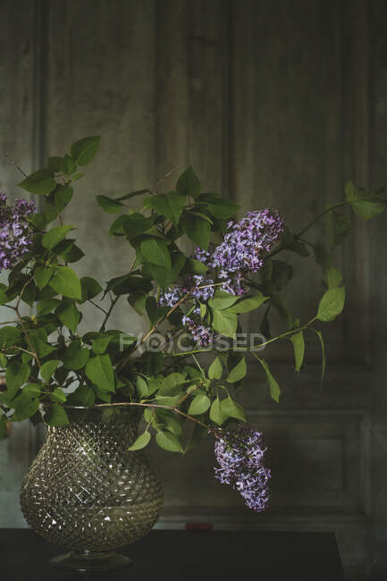 Lilac flowers in vase in front of door — Photo de stock