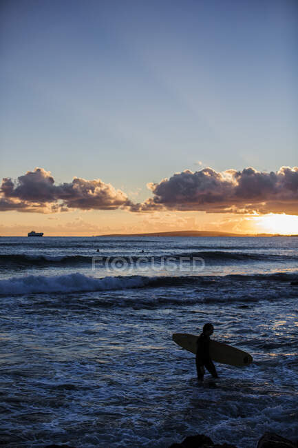 Silhouette of surfer on beach at sunset — Stock Photo
