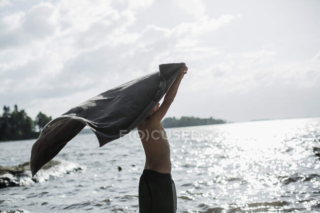 Мальчик с полотенцем у озера — стоковое фото