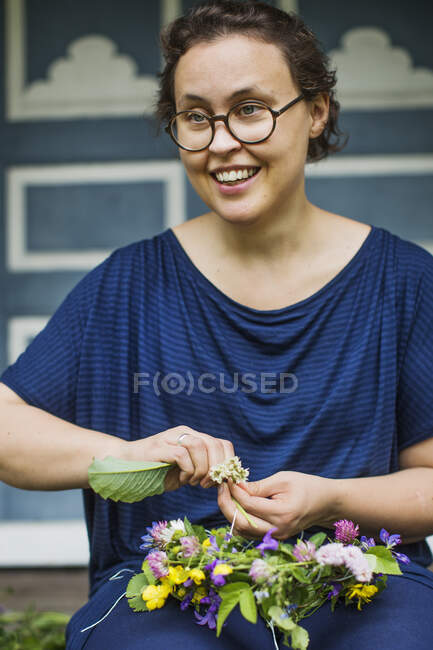 Улыбающаяся женщина делает цветочную корону Мидсоммара — стоковое фото