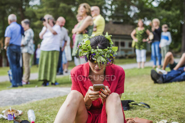 Frau mit Blumenkrone bedient Smartphone — Stockfoto