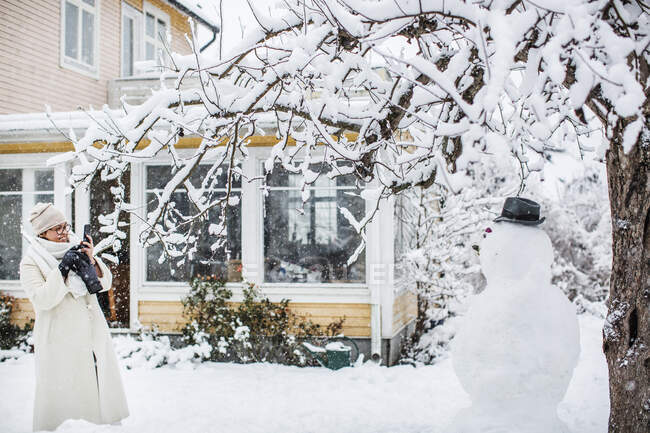 Жінка фотографує снігову людину — стокове фото