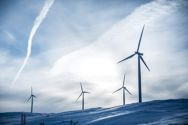 Низкий угол обзора ветряных турбин на снежном холме — стоковое фото