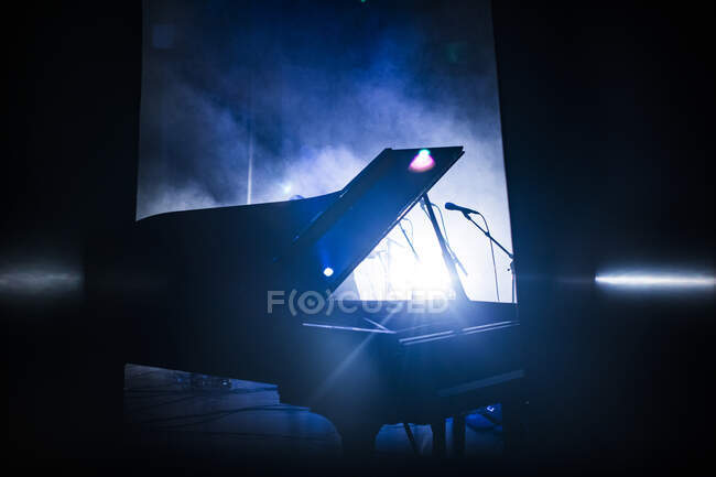 Piano in shadow on concert stage — Stockfoto