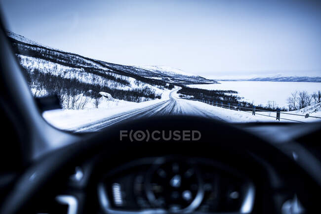 Steering wheel of car driving on snowy highway — Stock Photo