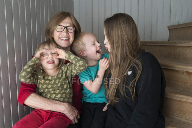 Woman sitting with her grandchildren on staircase — Foto stock