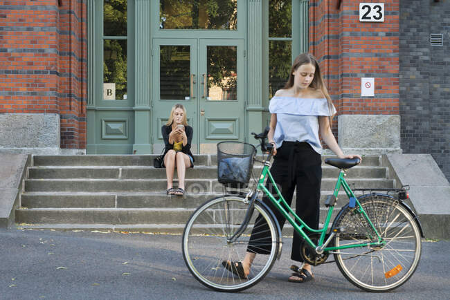 Sisters with bicycle in city — Stock Photo