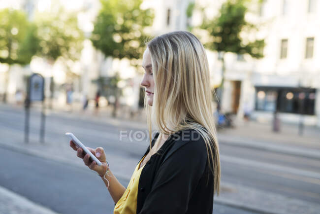 Mujer joven con teléfono inteligente en la ciudad - foto de stock
