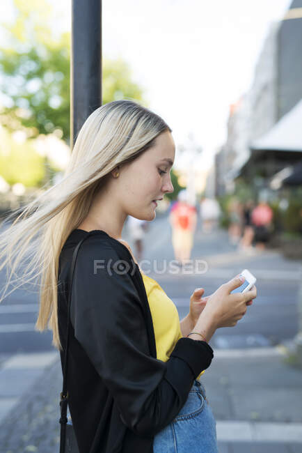 Молода жінка зі смартфоном у місті — стокове фото