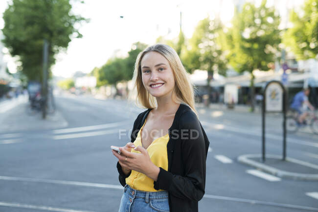 Jeune femme avec téléphone intelligent en ville — Photo de stock
