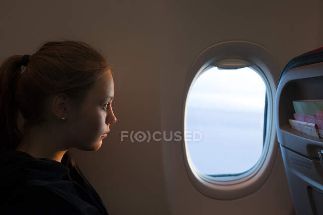 Teenage girl looking out airplane window — Photo de stock