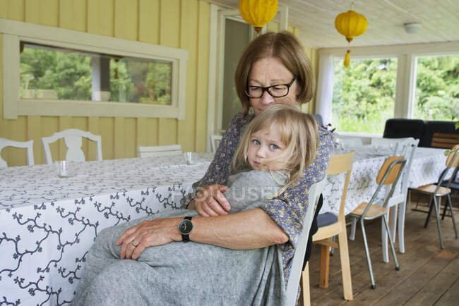 Girl sitting in her grandmother's lap at dining table — Foto stock