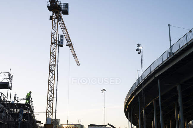 Trabalhador da construção em pé sobre andaimes por guindaste — Fotografia de Stock