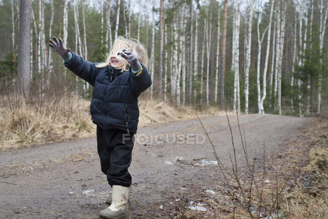 Girl wearing winter clothes walking on rural road — Stock Photo