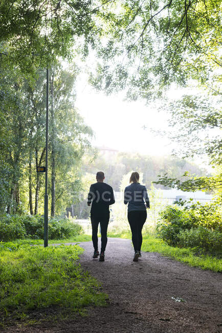 Man and woman jogging on trail in forest — Stock Photo