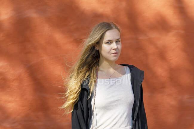 Блондинка волохата молода жінка біля помаранчевої стіни — стокове фото